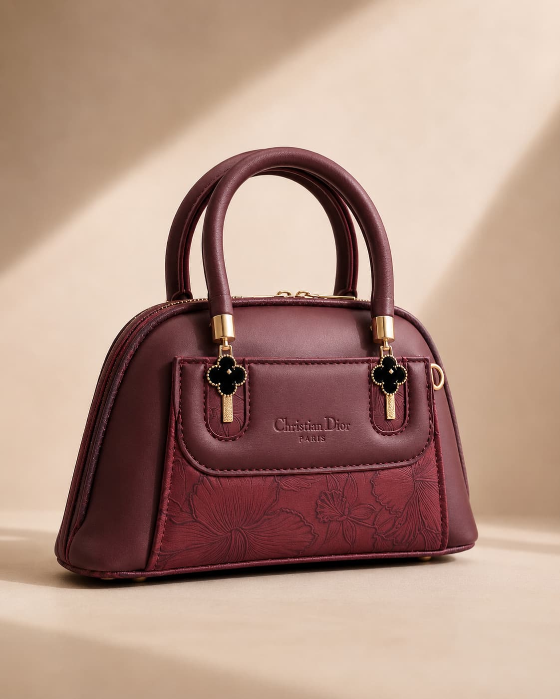 Burgundy wine maroon mini dome bowling bag for women with floral emboss detail gold hardware and black clover charm top handle luxury style 2026