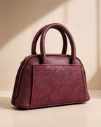Burgundy wine maroon mini dome bowling bag for women with floral emboss detail gold hardware and black clover charm top handle luxury style 2026