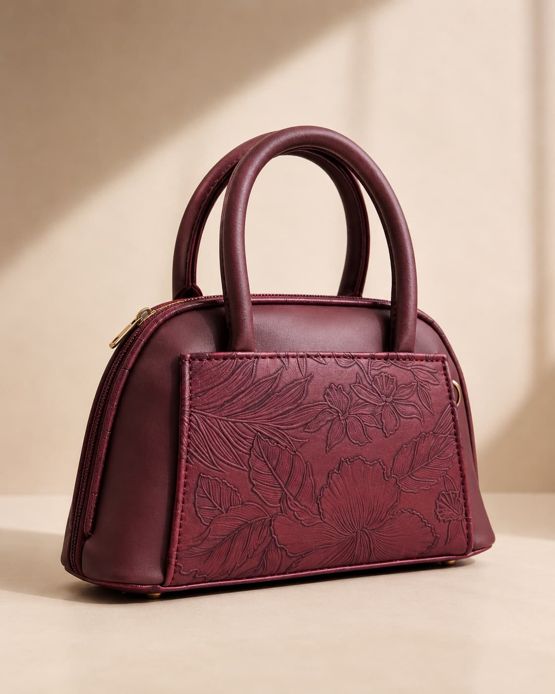 Burgundy wine maroon mini dome bowling bag for women with floral emboss detail gold hardware and black clover charm top handle luxury style 2026