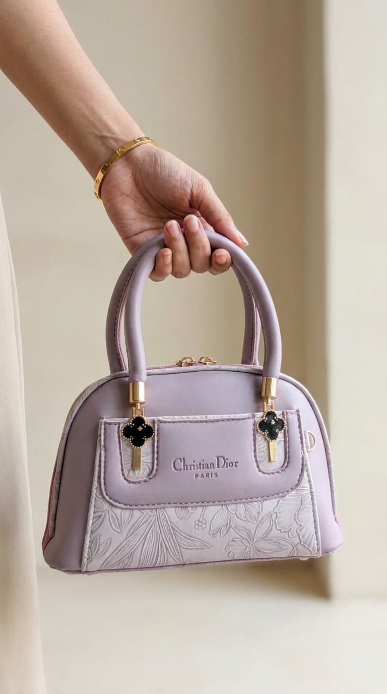 Lavender lilac mini dome bowling bag for women with floral emboss detail gold hardware and clover charm top handle luxury style 2026
