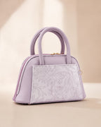 Lavender lilac mini dome bowling bag for women with floral emboss detail gold hardware and clover charm top handle luxury style 2026