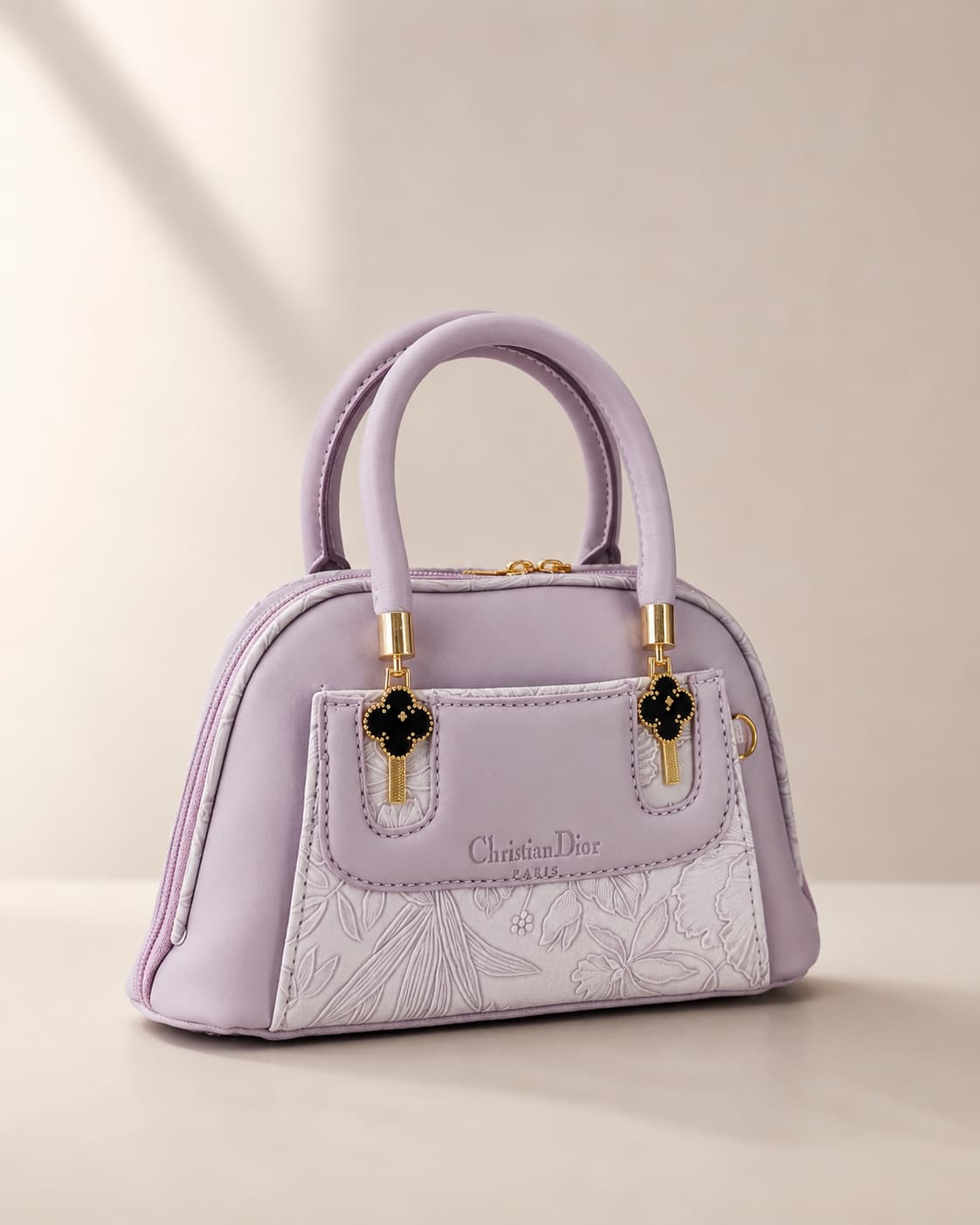 Lavender lilac mini dome bowling bag for women with floral emboss detail gold hardware and clover charm top handle luxury style 2026